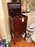 Front view of flatware chest with lid open showing compartments and flatware inside.