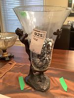 Front view of the vase showing the woman figurine holding the glass container filled with glass stones.