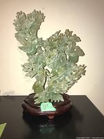 Front view of pale green glass carving showing main branch and blossoms