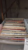 Bin of vinyl LP records stacked vertically in a plastic bin, showing various album spine edges.