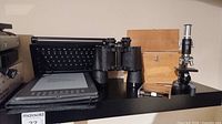 Overview of microscope, e-reader, binoculars, keyboard, and lens filters on shelf