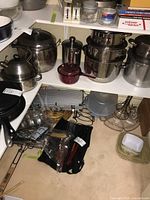 Overview photo showing several stainless steel pots, the maroon saucepan, and various kitchen items