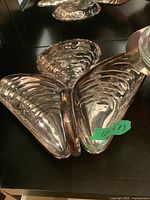 Top view of three-section shell-themed silver plated serving dish with handle showing hammered texture and reflective surface