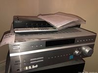 Full view of a silver Sony stereo receiver with remote control and manuals on top.
