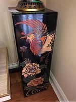 Side view of lacquered pedestal stand showing painted crane and flowers on black background