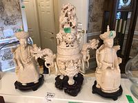 Photo showing the three resin figurines: two Asian male figures in traditional attire seated on black wooden bases and a large ornate urn with dragon carvings.