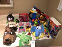 Overview of the toy lot showing Disney PEZ dispensers, Cube World games, boxed Space Quest game and assorted plush and plastic toys