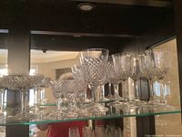 Assorted crystal stemware on glass shelf, mixing Alana pattern and non-Waterford glasses