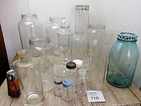 Full view of the lot with all glass bottles and jars arranged on wooden surface showing variety and size.
