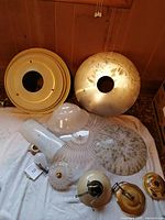 Overall view of assorted vintage ceiling lamp parts and glass shades arranged on a surface, showing variety and condition.