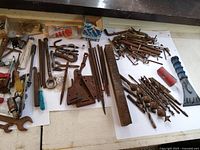 Long shot of the assorted tools including wrenches, screwdrivers, drill bits, and screws with some visible rust.