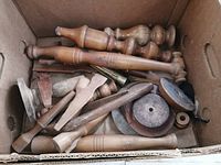 Box with assorted turned wooden spindles, lamp bases, and structural wood pieces in used condition.