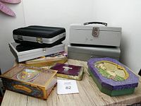 Two photos of a variety of metal and tin boxes arrayed on a wooden surface including metal cash boxes and decorative tin boxes.