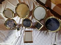 Full set of nine vintage brass picture frames displayed on fabric background.