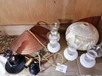 Photo showing the metal lamp bar frame, spun fibreglass globe lampshade, three glass milk white chimneys with scalloped gold edges, and attached wiring all laid out on a surface.