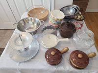 Wide view of assorted bowls, ceramic pots, colanders, and glass jar on table