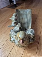Front view of ceramic dish showing large bird head and three smaller birds on the edge
