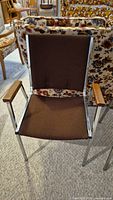 Brown metal frame chair with brown fabric seat and back, wooden armrests visible