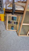 Multicolored stained glass panel with wooden frame leaning on floor