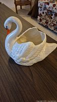 Side view of white ceramic swan planter showing detailed feather work and smooth glossy finish