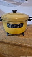 Front view of vintage yellow Toastess electric pot deep fryer with lid and black knob handle.