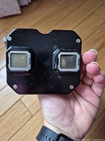 First black View-Master viewer held in hand showing twin lens eyepieces and top surface.