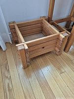 Photo showing the smaller wood plant stand square box and legs on hardwood floor.