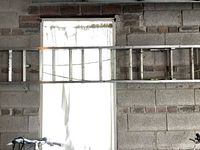 16-foot aluminum extension ladder hung horizontally against a brick wall over a window.