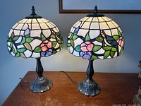 Two Tiffany style table lamps side by side on wooden surface showing overall appearance