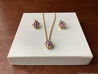 Necklace and earrings set displayed on white textured platform showing design and size.