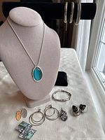 Photo showing 8 pieces of assorted vintage jewelry including necklace with turquoise stone pendant, three bracelets, and several pairs of earrings.