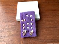 Photo showing all earrings on purple display pad, including white, pink, peach, lavender pearl studs and pearl cluster earrings with gold backing