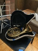 French horn inside open hard case on a table with mouthpiece and accessories visible