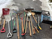 Full view of garden tools and dolly on asphalt with snow surrounding the area