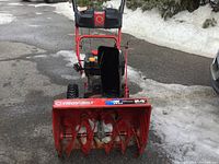 Front view of red Troy-Bilt snow blower showing two-stage auger and rotating chute