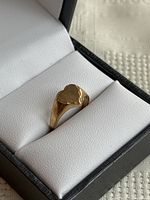 Three-quarter view of heart-shaped signet ring in black jewelry box showing top and right side profile