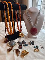 Multiple necklaces, brooches, pins and earrings displayed on table and stands