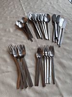 Full layout of all cutlery pieces grouped by type in five piles on tablecloth