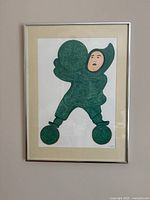 Full view of the framed Inuit art print showing the figure and frame, mounted on a wall.