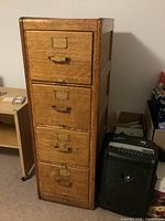 Full-height view of vintage oak filing cabinet with four drawers and brass hardware