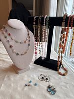 Lot displayed on fabric surface with bust and T-bar stands showing multiple necklaces and earrings