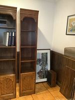 Two narrow vintage wooden bookcases side by side with shelving and bottom cabinets.