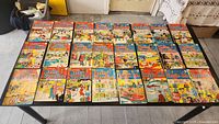Full view of all 24 comics laid out on a table, showing colorful covers with various Archie characters and series titles.