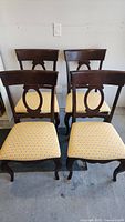 Four solid wood dining chairs grouped together showing overall condition and style