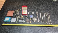Full view of the lot including brooches, pins, necklaces, earrings, and pendants arranged in rows with a measuring tape showing size references