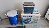 Three coolers: Rubbermaid jug on left, Coleman cooler atop Mobicool box on right.