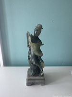 Front and side views of the carved stone geisha girl statue on a rectangular base.