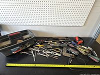 Wide view of the miscellaneous hand tools spread out on the table including wrenches, pliers, screwdrivers, tape measure, and lock pliers.
