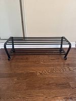 Front view of black metal boot rack showing its construction and wear.