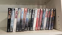 Seventeen NCIS DVD box sets lined up on a shelf with visible season numbers 1 through 17, mostly sealed in plastic shrink wrap.
